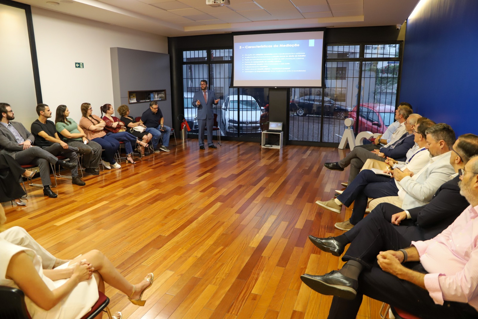 A foto mostra o desembargador Alexandre palestrando com o público assistindo.