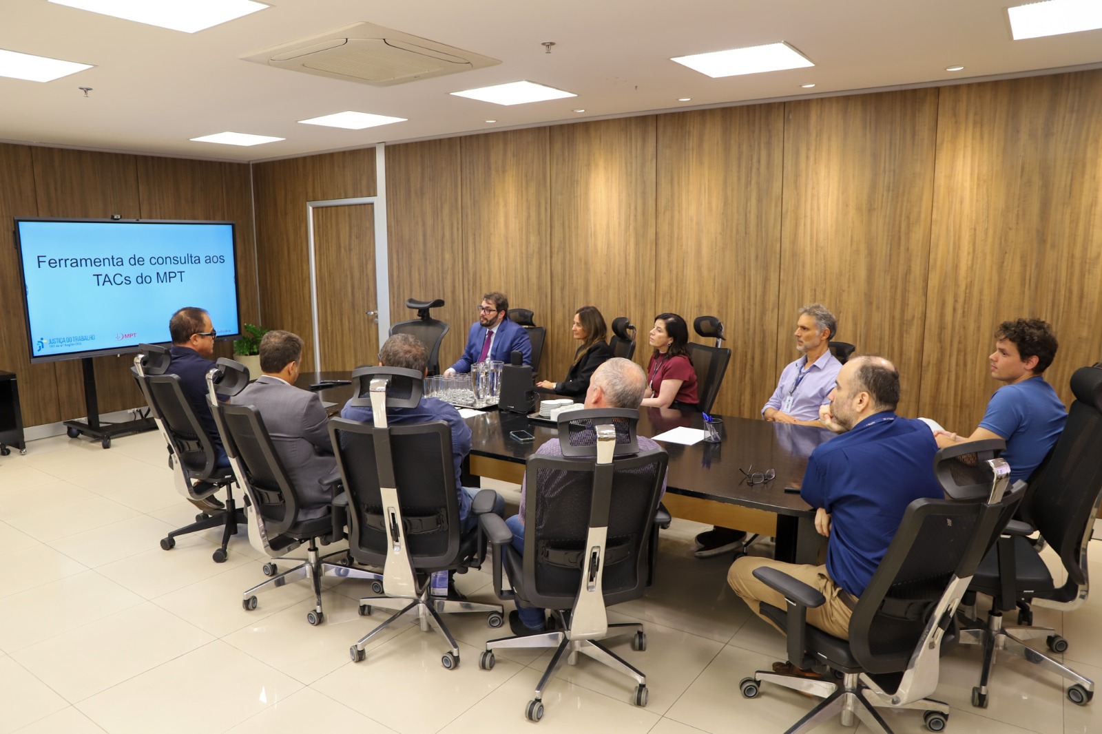 A foto mostra pessoas ao redor de uma mesa.
