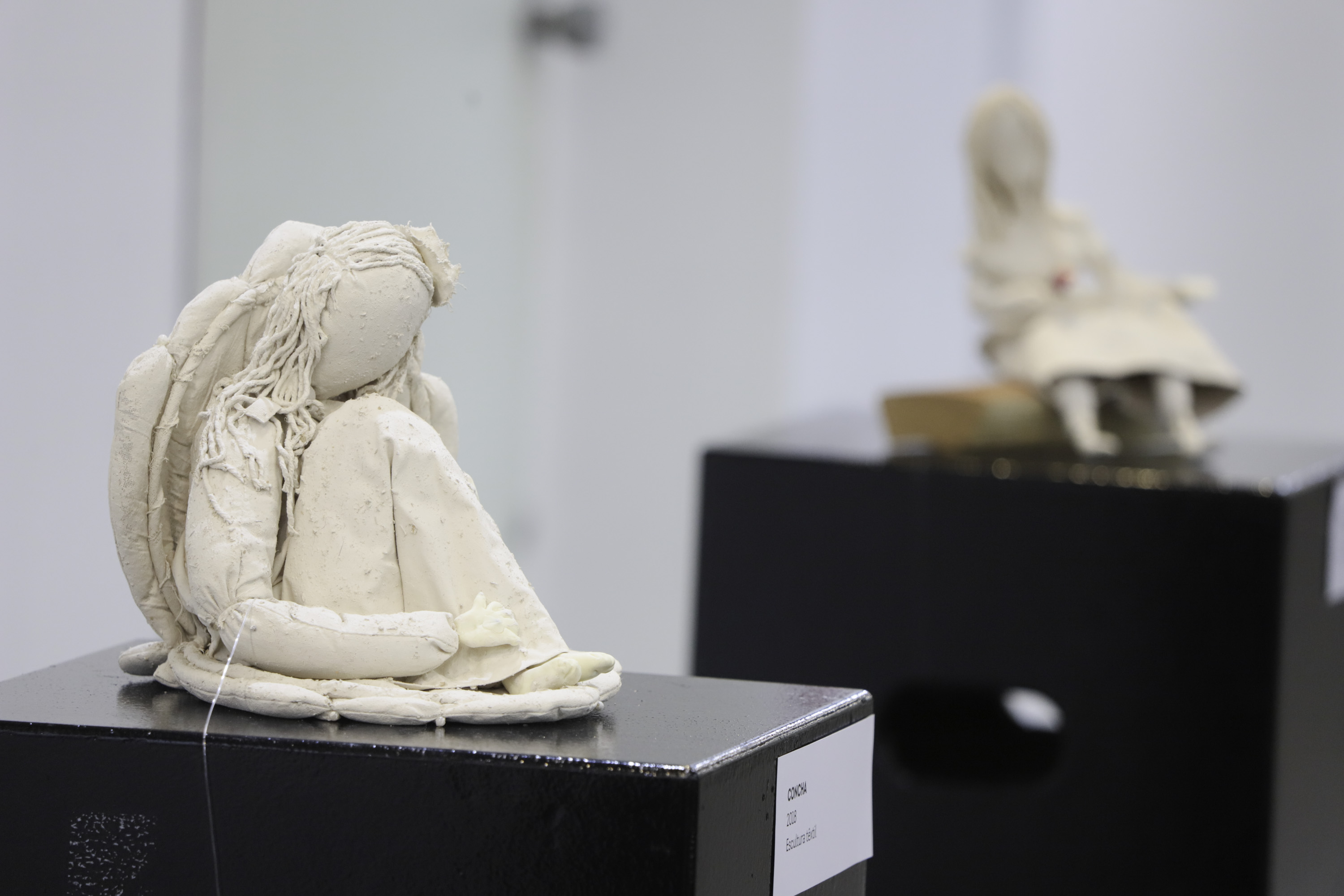 escultura sentada com outra ao fundo