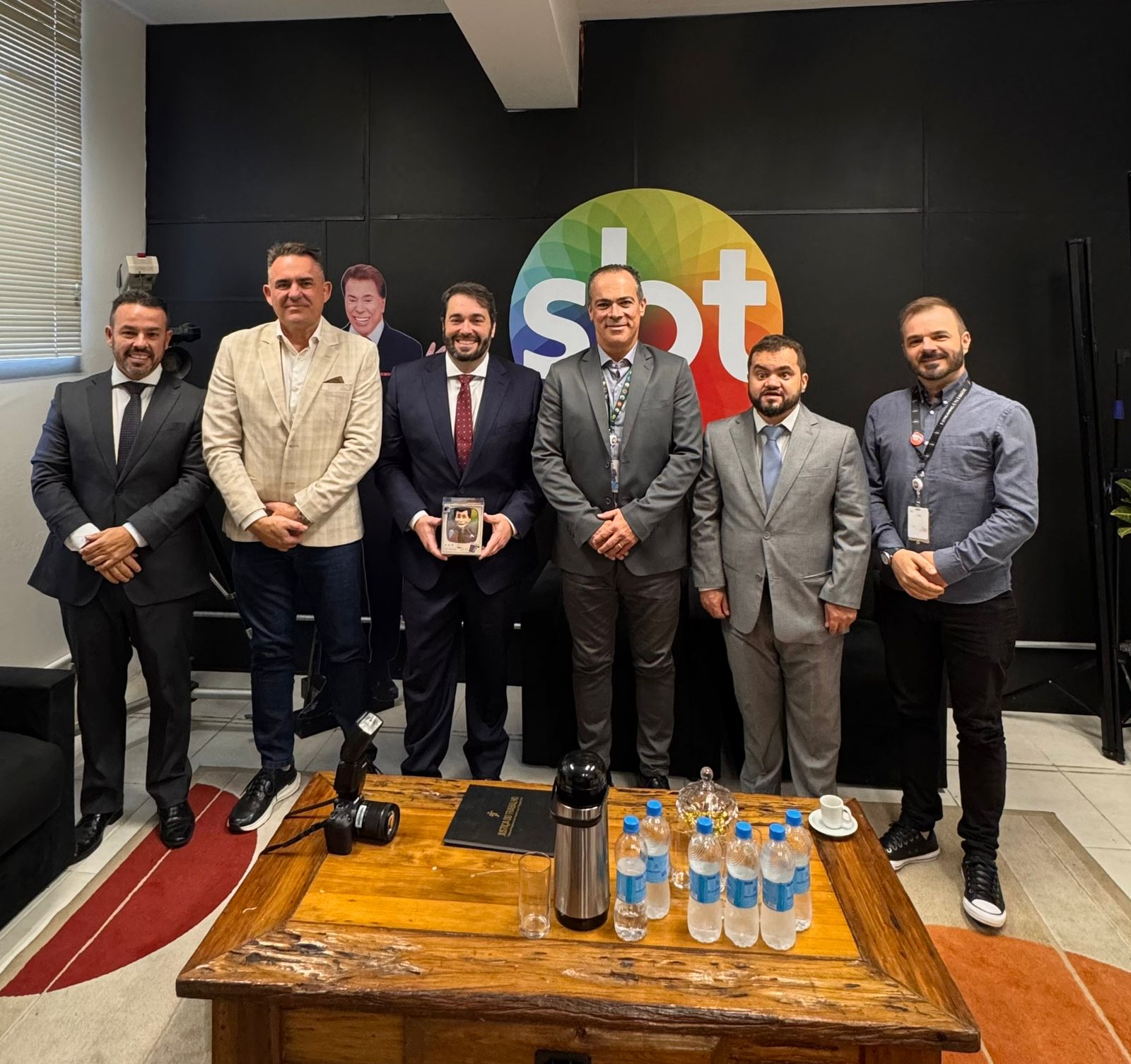 A foto mostra seis pessoas posando para foto na visita institucional ao SBT.