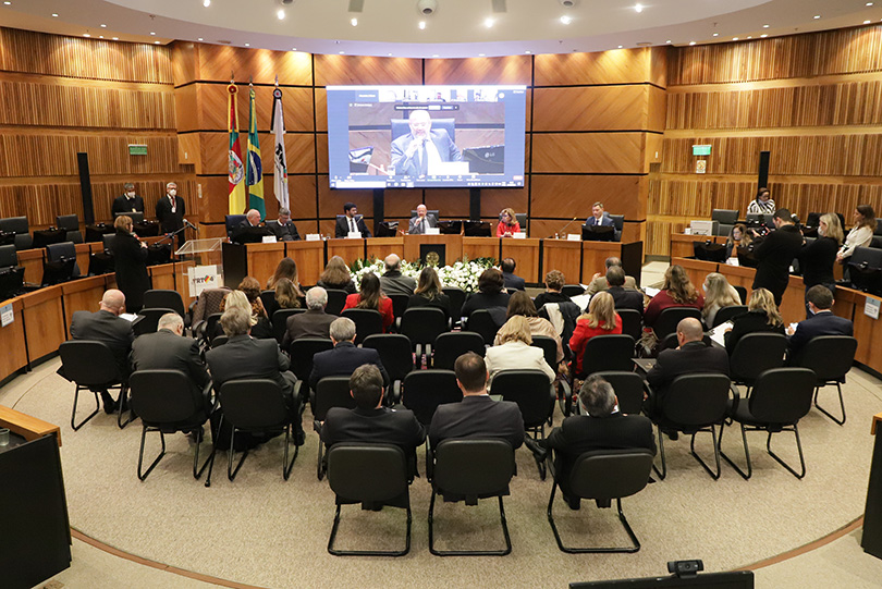 Mesa oficial, autoridades na nave e telão mostrando o desembargador Mancilha, presidente do Coleprecor