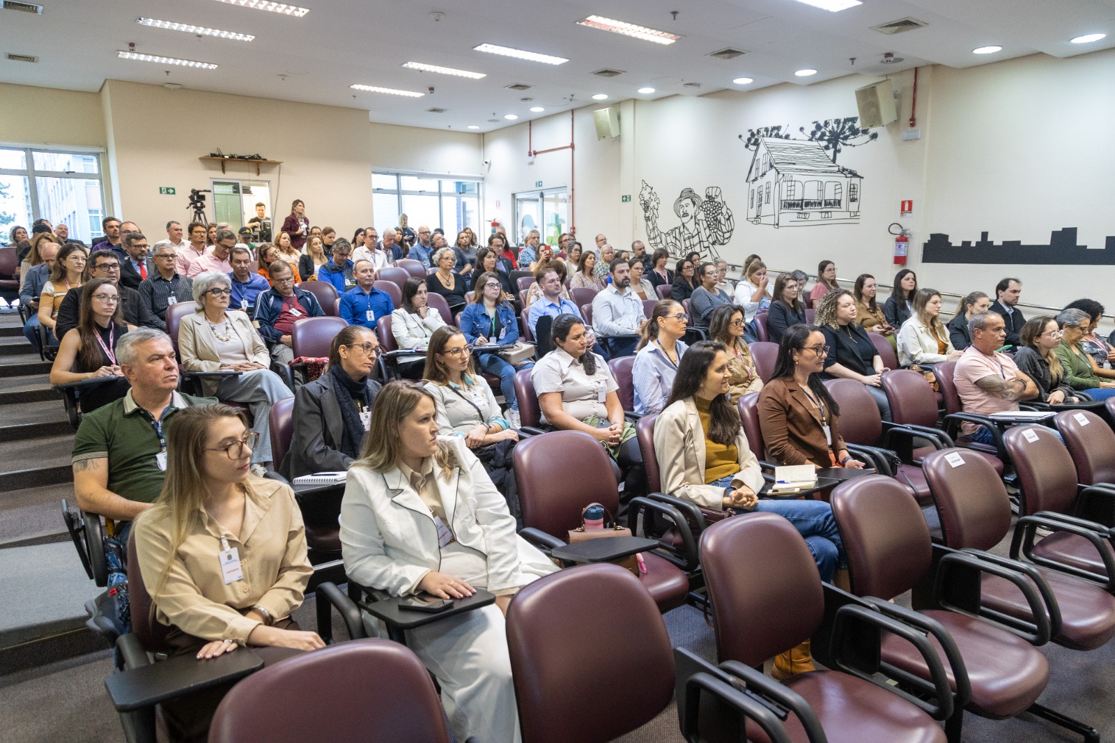 público da palestra sentado nas cadeiras do audiório.