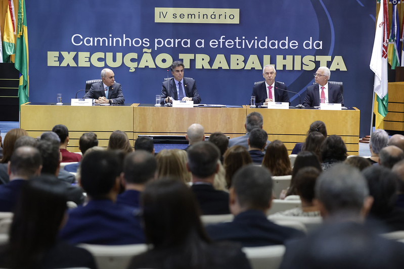 Foto em ângulo aberto, mostrando público e mesa de autoridades