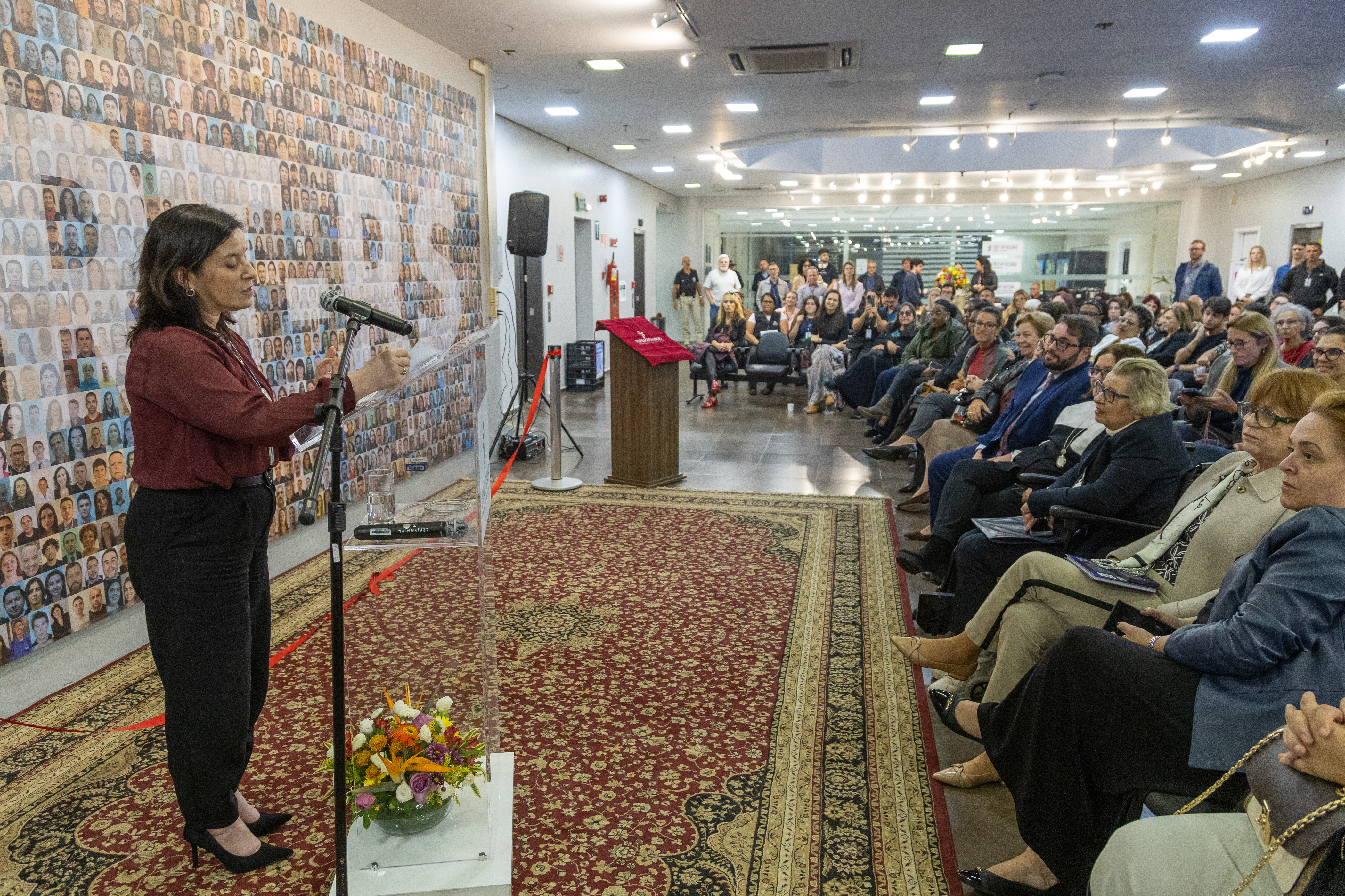 A foto mostra a servidora Enilda discursando em frente ao público.