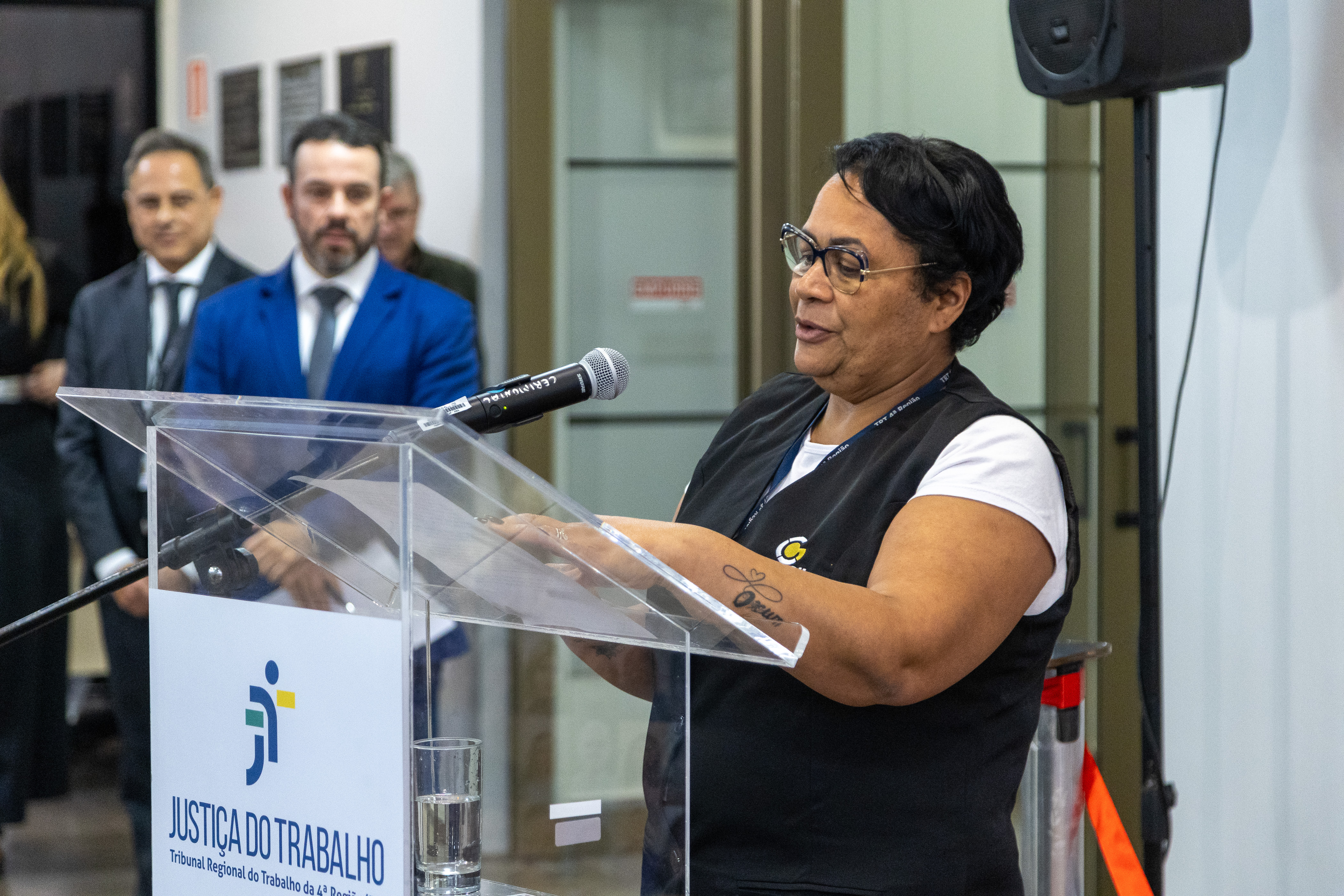A foto mostra a trabalhadora Edilene discursando em frente ao público.