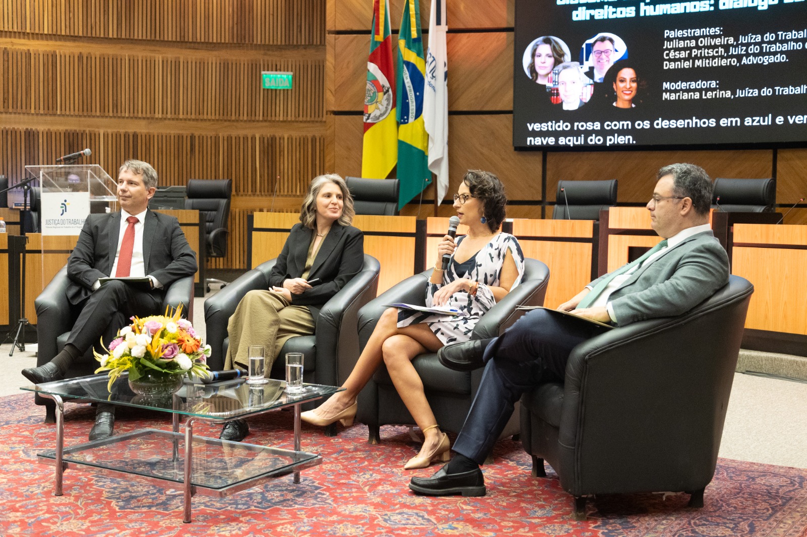 Quatro participantes do painel sentados em sofás na nave do plenário