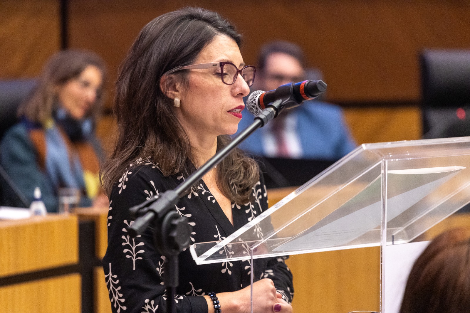 Valéria é branca e de cabelo preto liso. fala ao microfone do púlpito. 