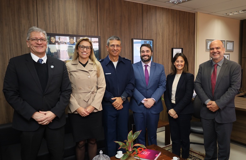A fotografia mostra os presentes na reunião, de pé, lado a lado, sorrindo