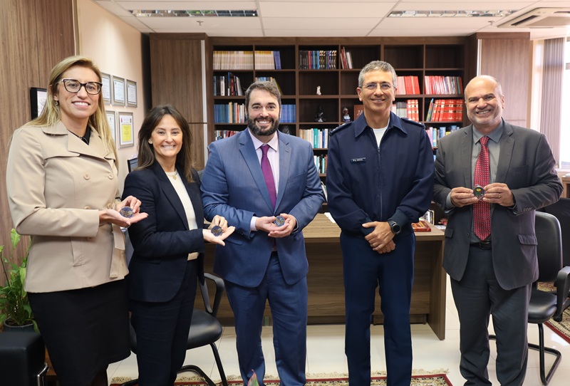 A fotografia mostra os presentes, de pé, estando os representantes do Tribunal segurando medalhas arredondadas e metálicas recebidas de presente.