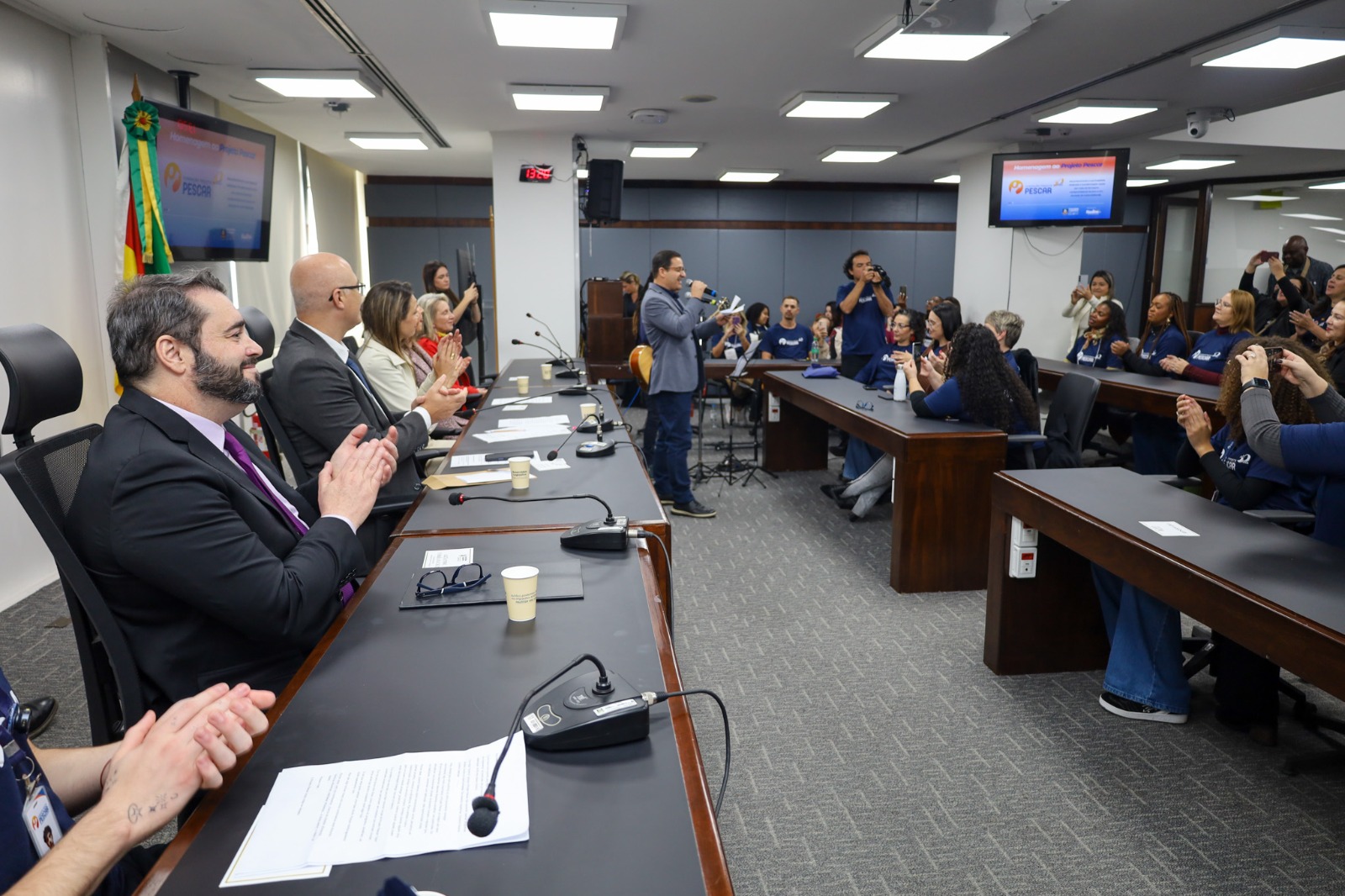 A foto mostra autoridades e público de lado.