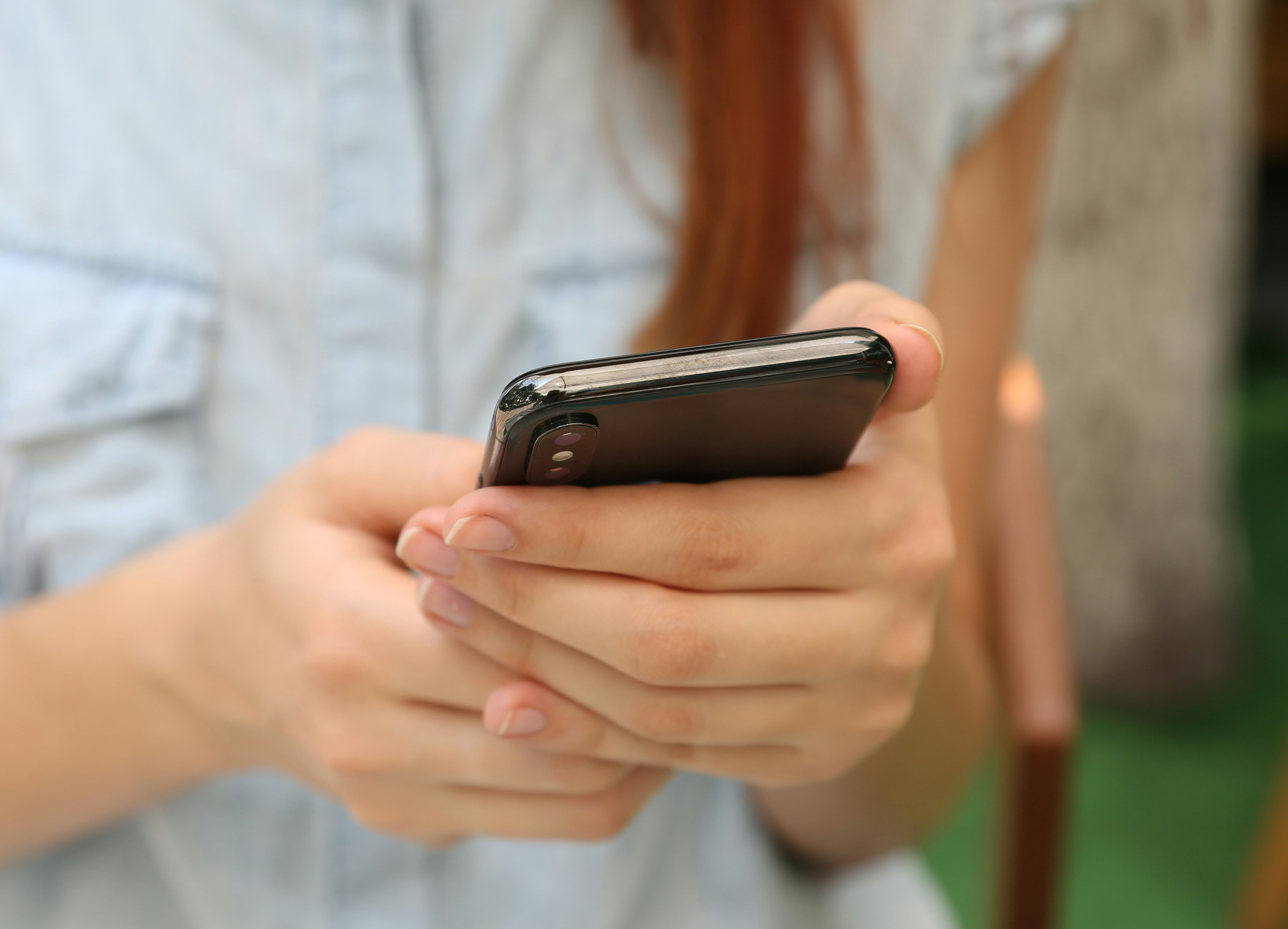 Mãos femininas seguram celular.