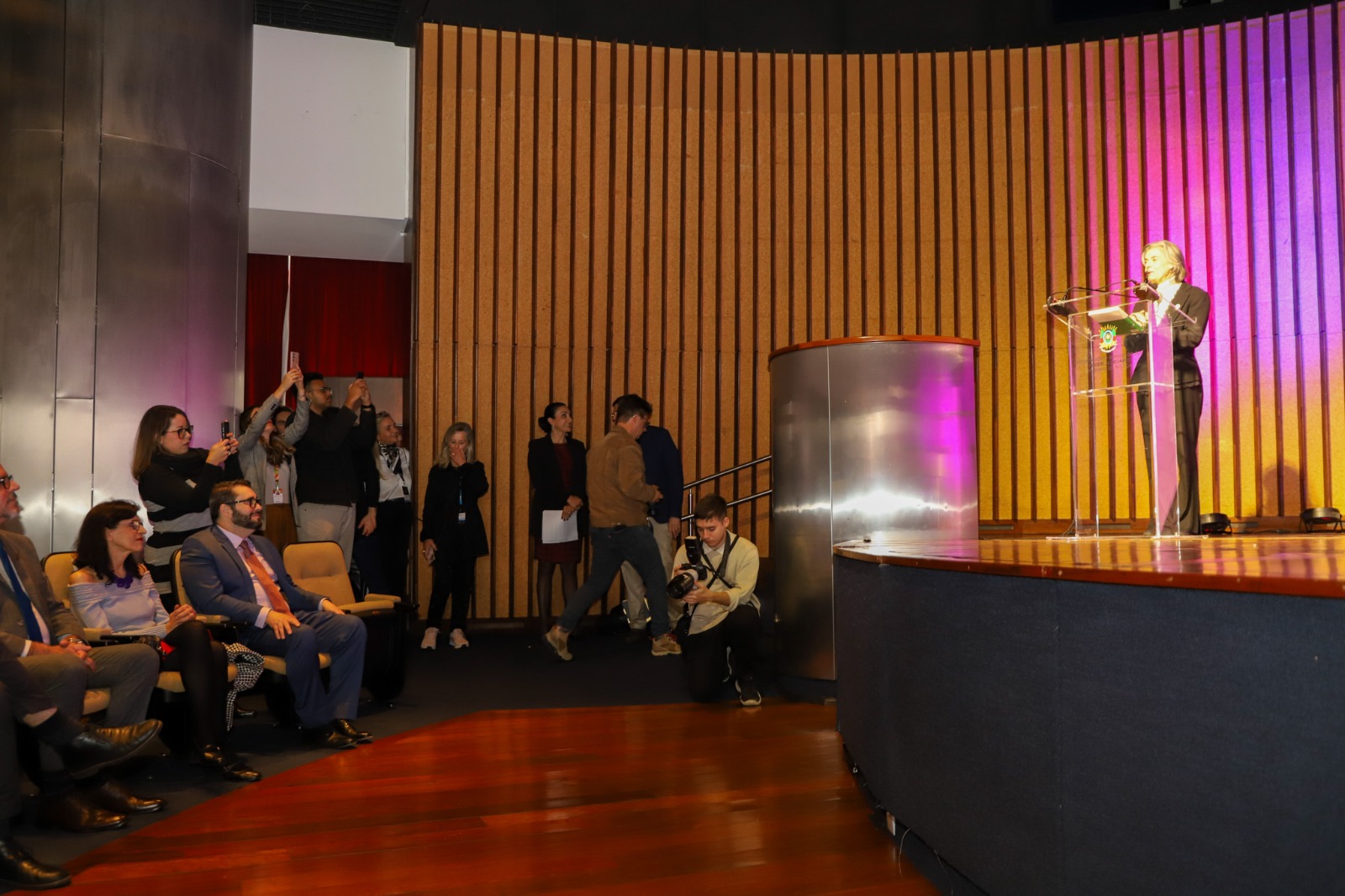 A foto mostra a ministra carmen palestrando e o des. alexandre assistindo.