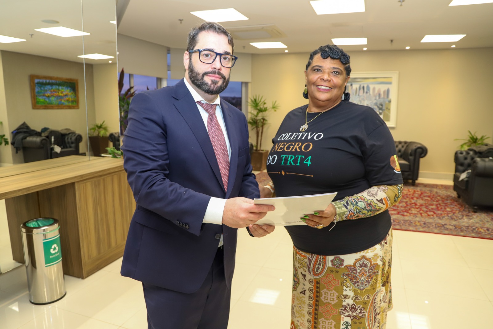A foto mostra a servidora Gládis entregando uma carta de intenções ao presidente Alexandre.