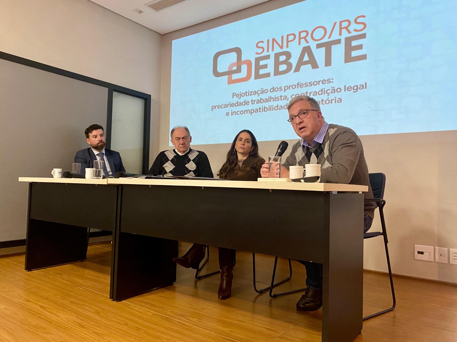 Mesa de debate do Sinpro, desembargador Cassou com o microfone discursando