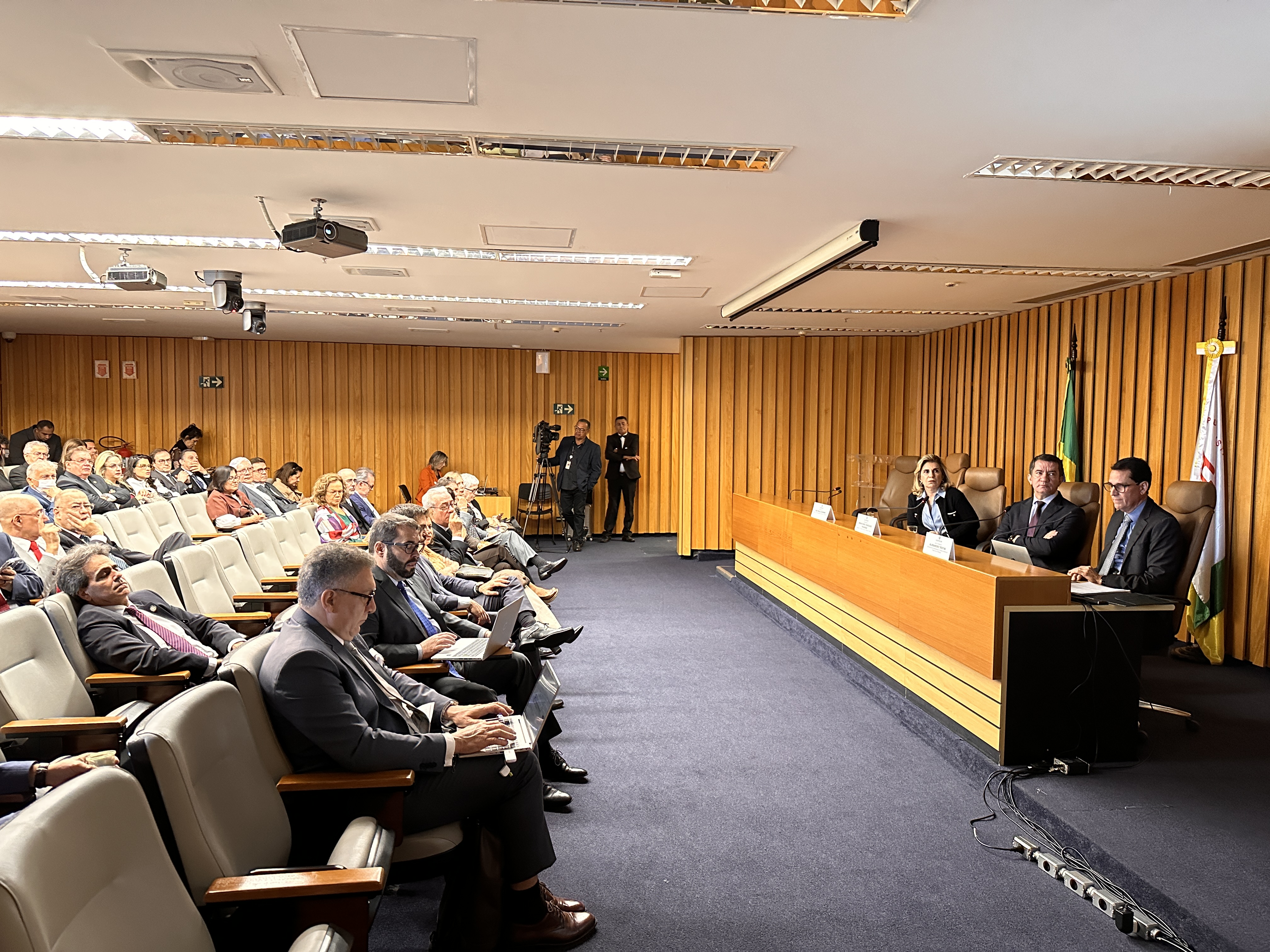 A foto mostra várias pessoas num auditório acompanhando uma palestra.