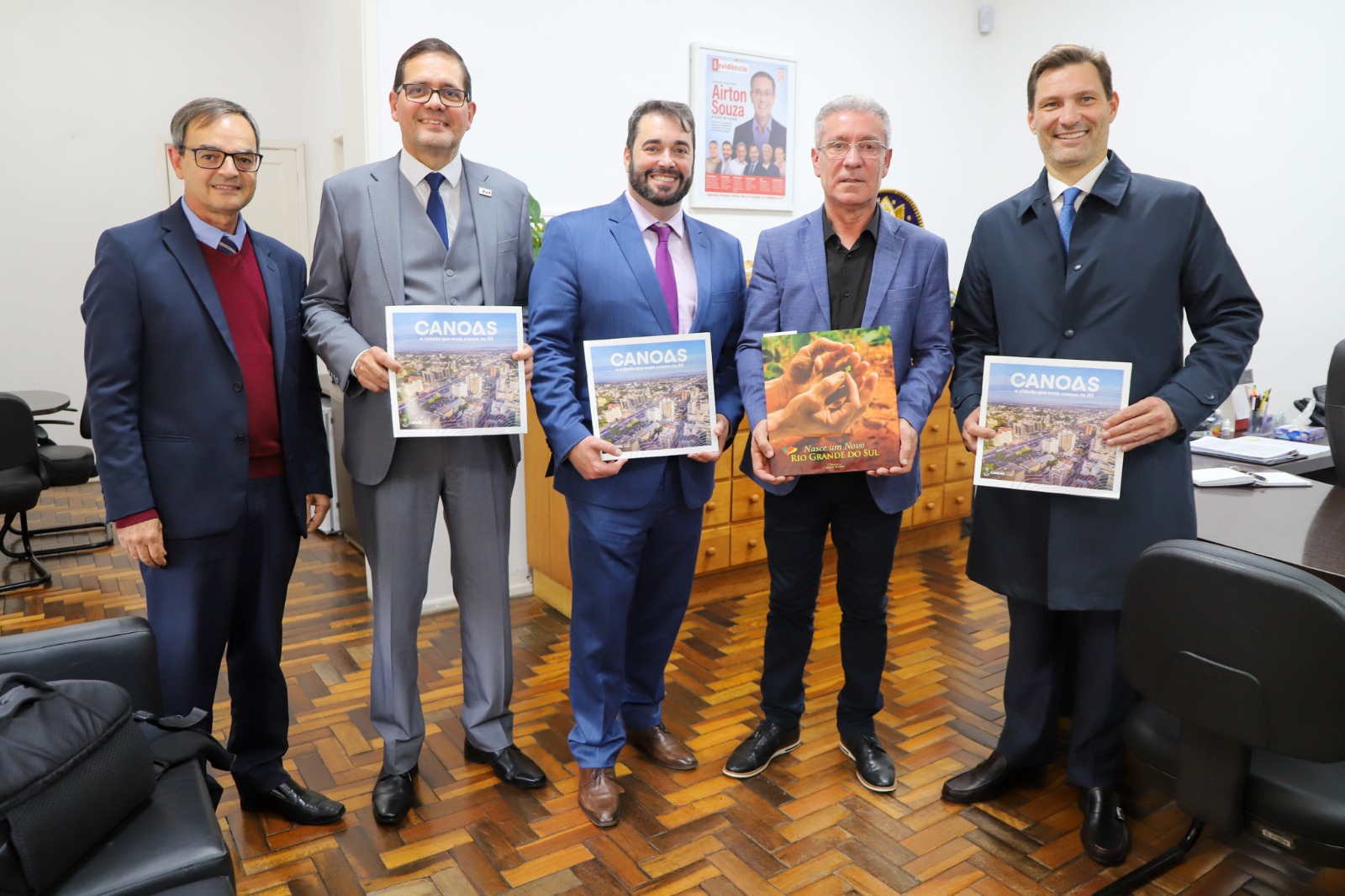 A foto mostra cinco pessoas posando para fotos com livros em mãos.