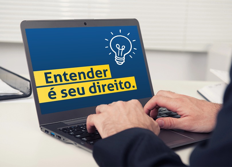 mãos de uma pessoa usando um notebook. Na tela aparece o texto "entender é seu direito" e o desenho de uma lâmpada acesa.