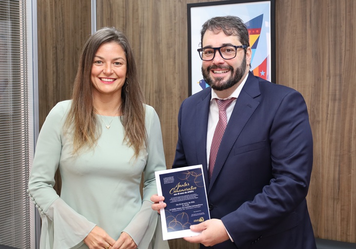 A fotografia mostra a vice-presidente da APMPA entregando o convite, em mãos, ao presidente do TRT-RS