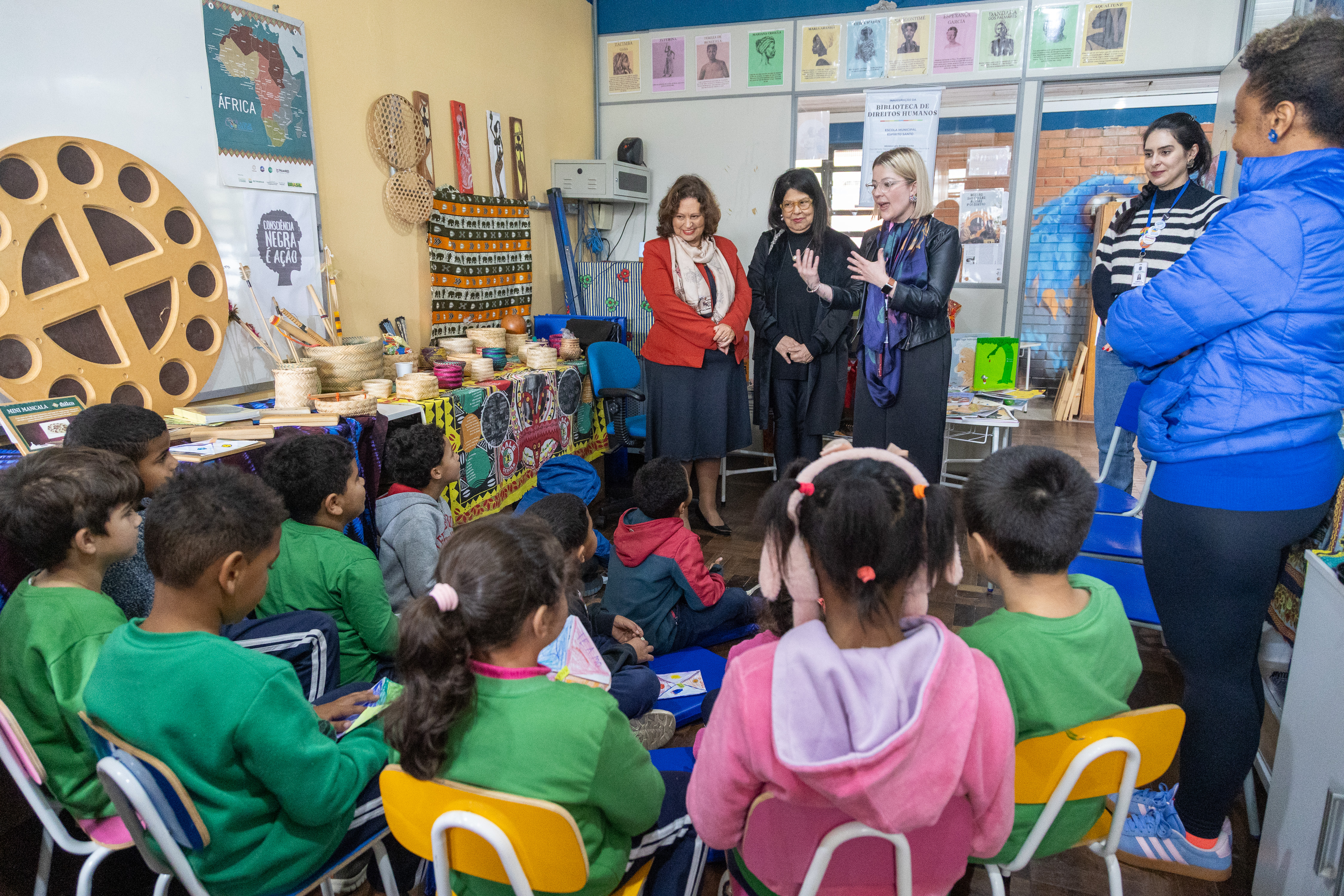 A foto mostra crianças de costas e a comitiva do TRT-RS falando com os alunos.