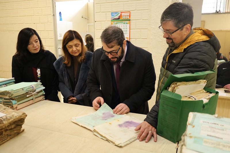 A fotografia mostra o presidente e comitiva folheando um processo recuperado no arquivo.