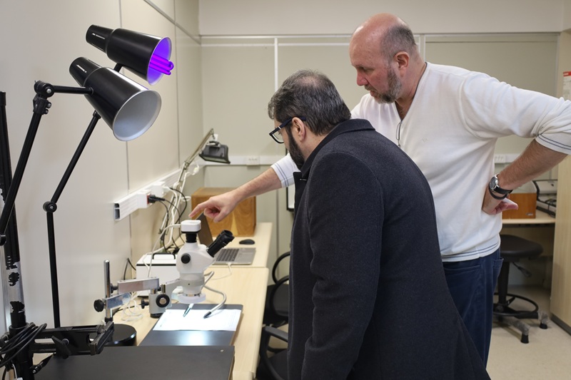 A fotografia mostra o chefe da Divisão de Perícias explicando ao presidente sobre o funcionamento de equipamentos utilizados para a realização das perícias.