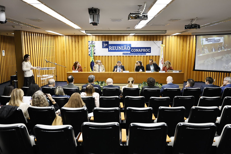 Foto em ângulo aberto do evento, mostrando público e mesa de autoridades.
