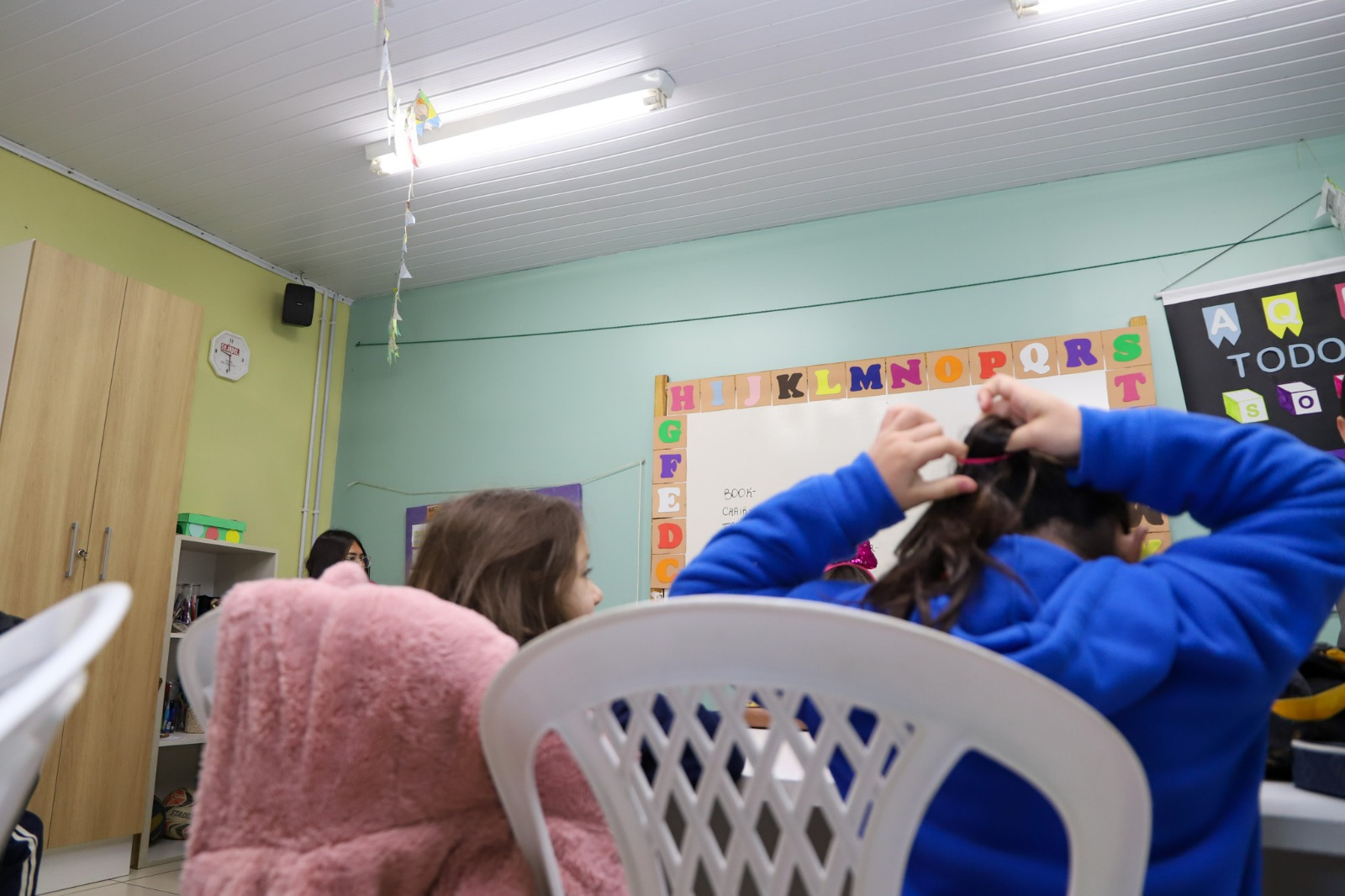 A foto mostra crianças em aula de costas.