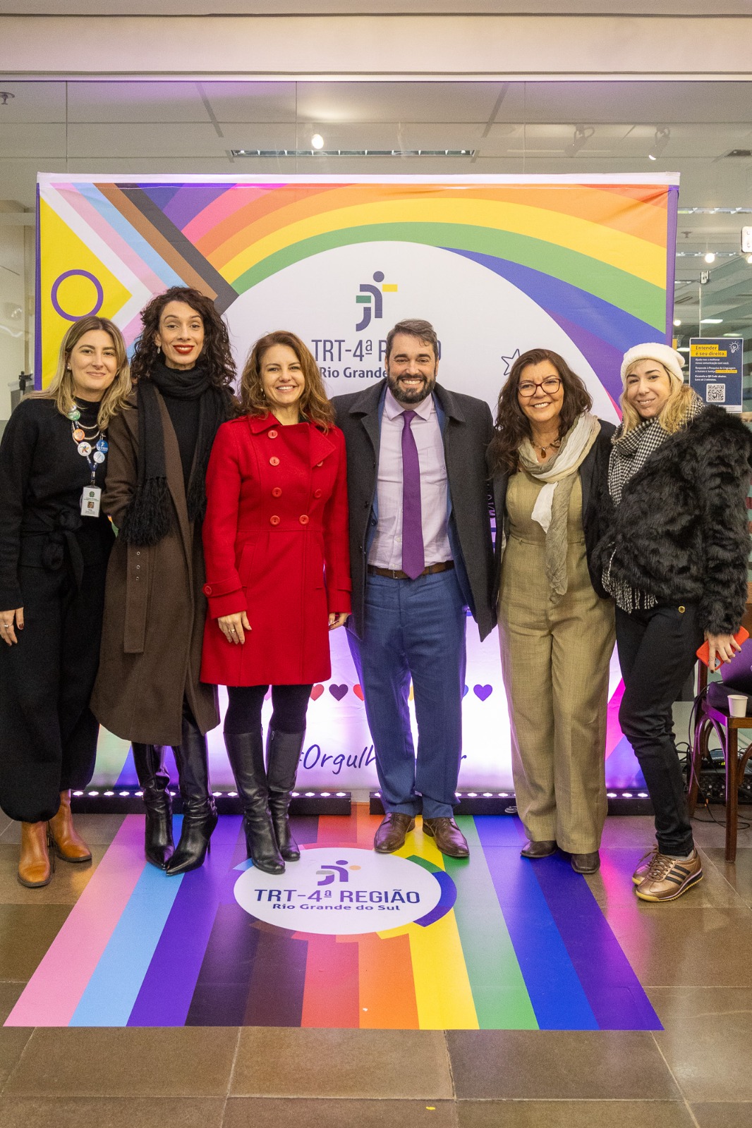 A foto mostra diversas pessoas posando para foto em frente ao painel da diversidade