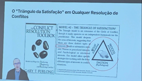 Telão mostra imagem do juiz Fernando Hoffmann abaixo, à esquerda. Ao fundo, há tele compartilhada com conteúdo em Inglês.