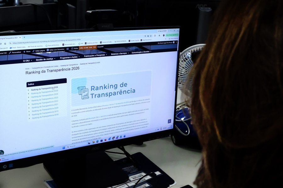 A imagem mostra uma pessoa em frente a uma tela de computador com a página do ranking da transparência do CNJ aberta.