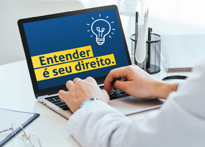 Pessoa digita em um notebook. A tela azul exibe o desenho de uma lâmpada e o texto em faixas amarelas: "Entender é seu direito."