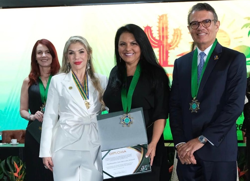 Desembargadora Tânia com medalha e diploma, em foto posada com outras pessoas.