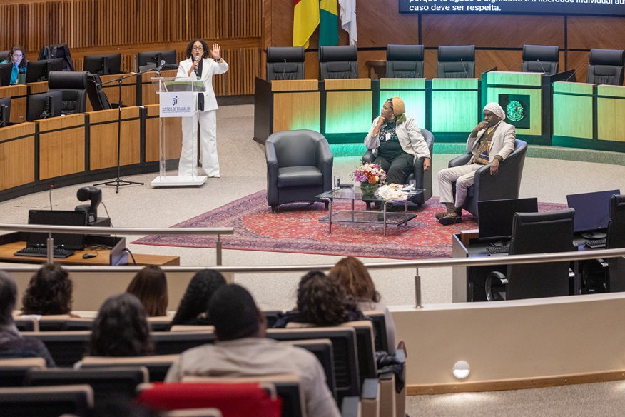 Foto em ângulo aberto do terceiro painel, mostrando parte do público de costas, e os painelistas na nave do plenário