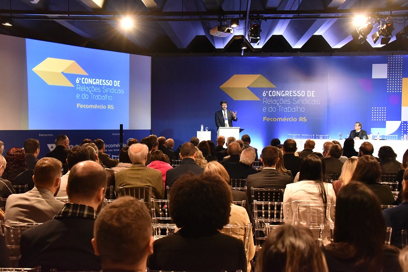 Foto em ângulo aberto do evento, mostrando público e palco