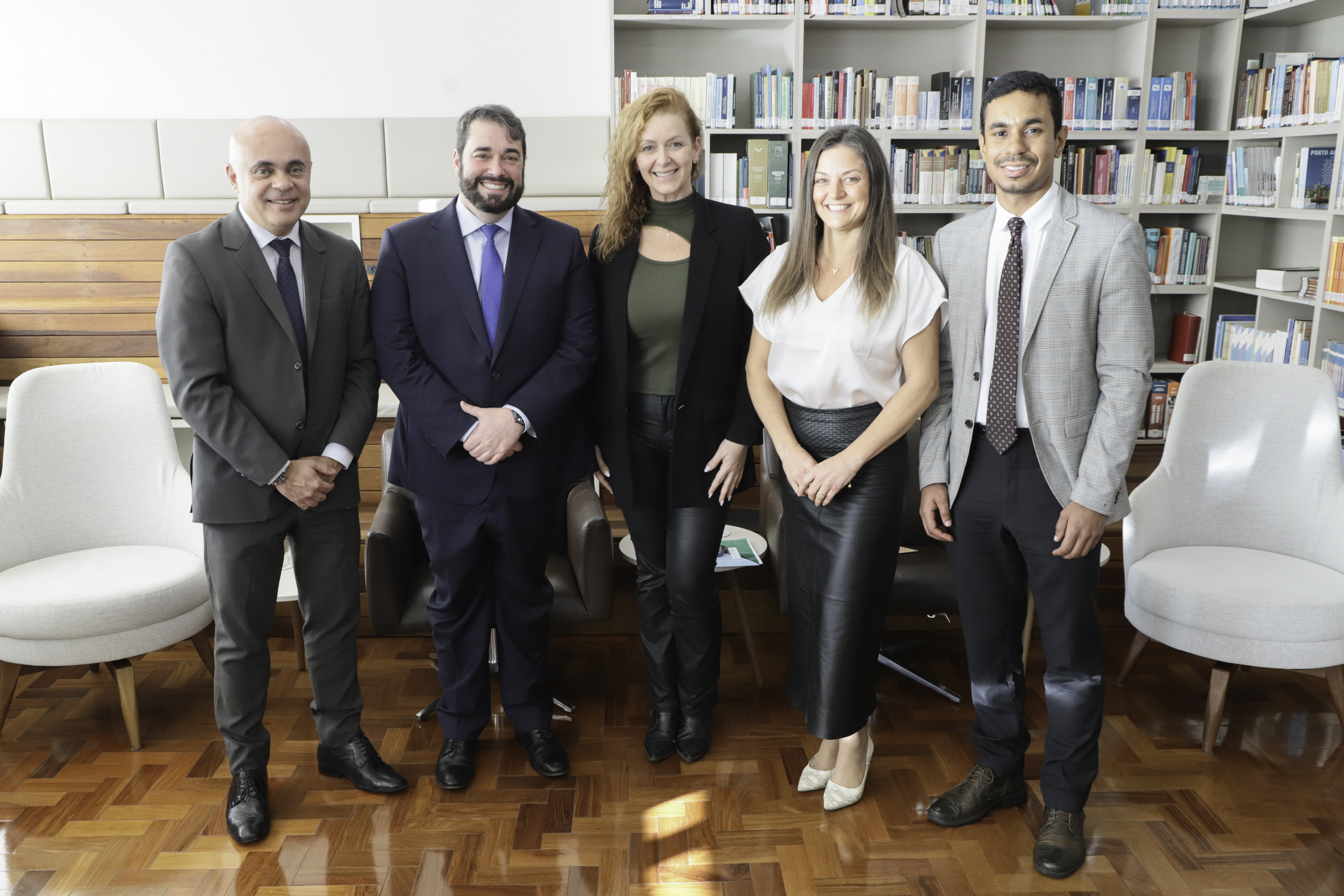 Cinco pessoas de pé posam para a foto. 