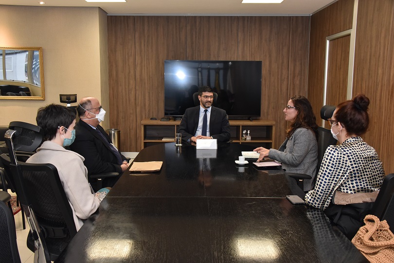 Foto da reunião, mostrando os participantes sentados à mesa.