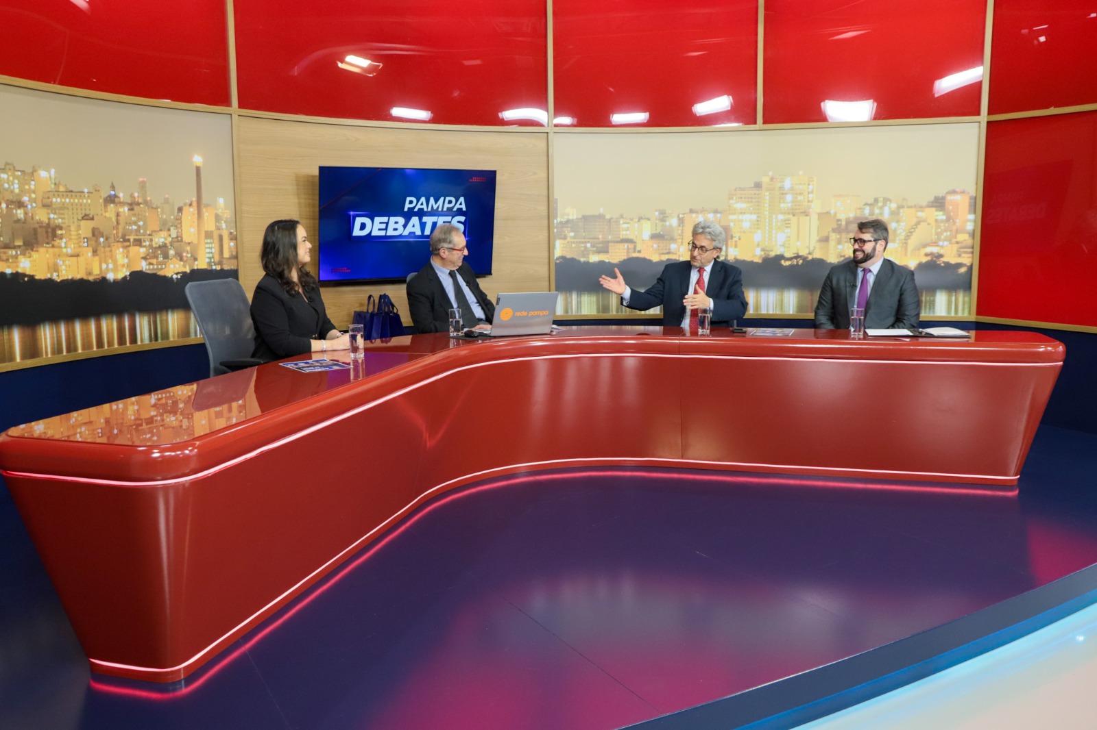 A foto mostra a bancada de fundo com participantes do programa.