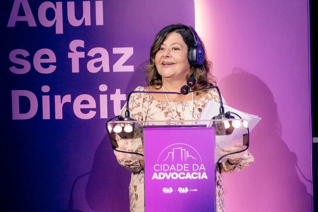 Carmen Gonzalez fala de pé no púlpito, usando um fone de ouvidos. 