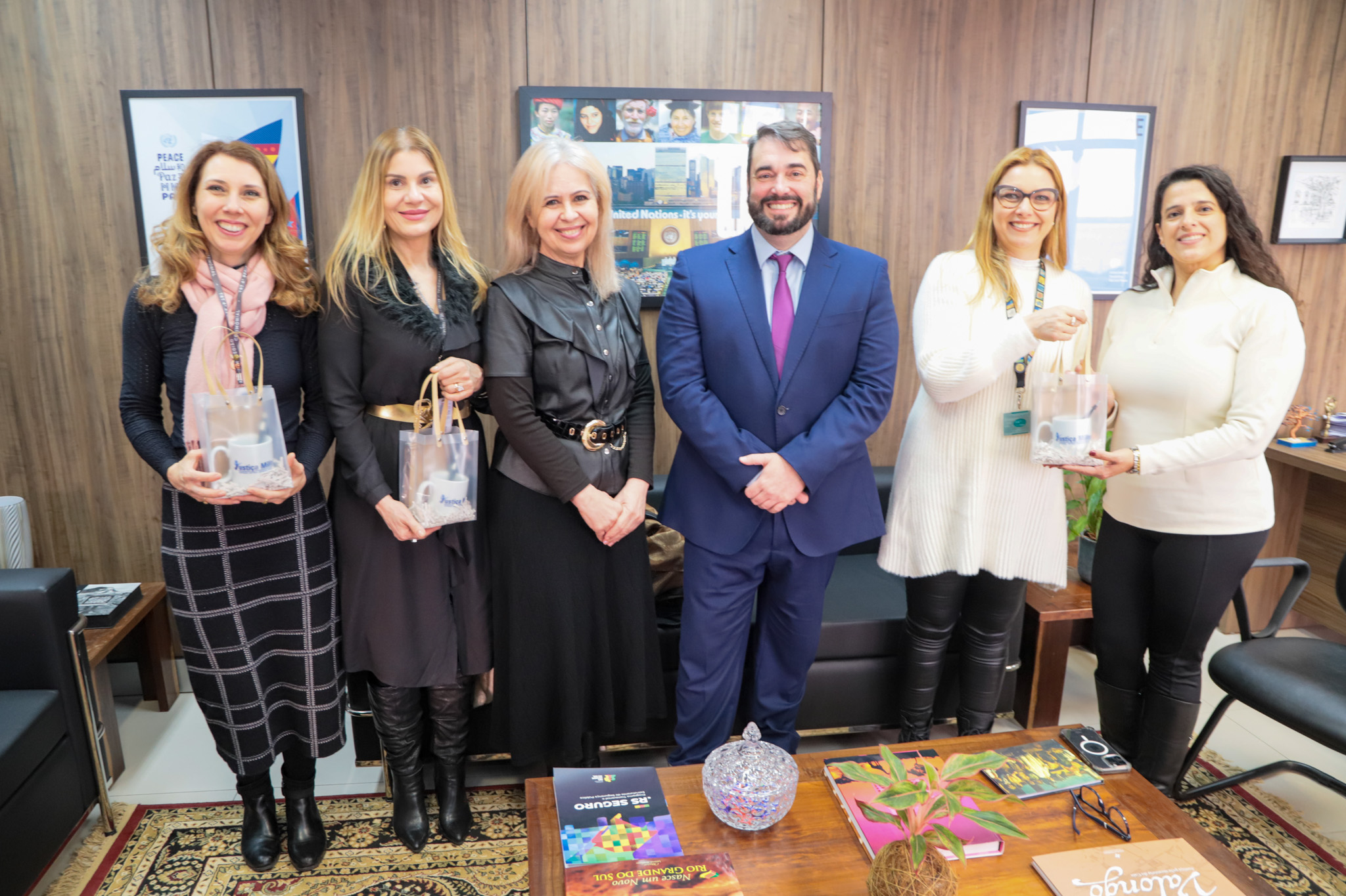 A foto mostra seis pessoas posando para foto com presentes sendo entregues.