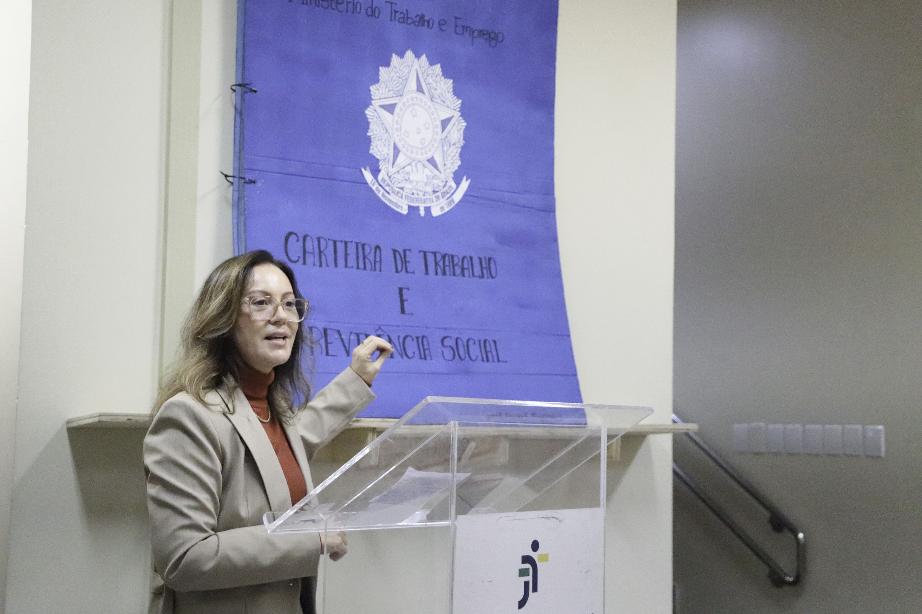 Adriana fala no púlpito com a obra ao fundo