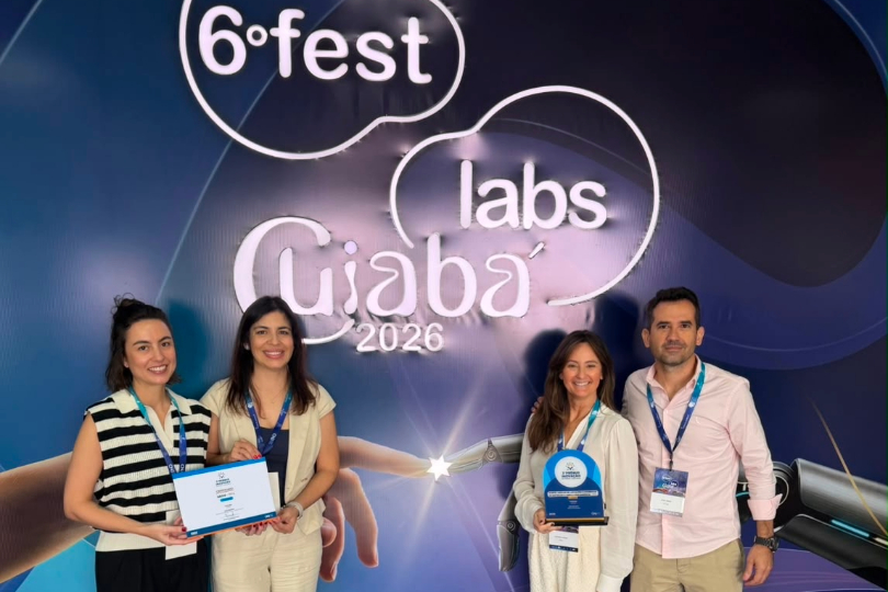 Três mulheres e um homem recebem a premiação. Ao fundo, há um painel azul com a inscrição em branco: 6º FestLabs - Cuiabá, 2026