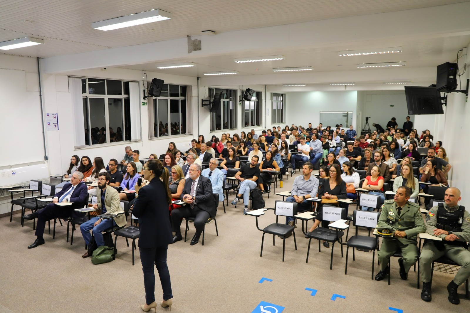 A foto mostra a juíza Aline falando ao público