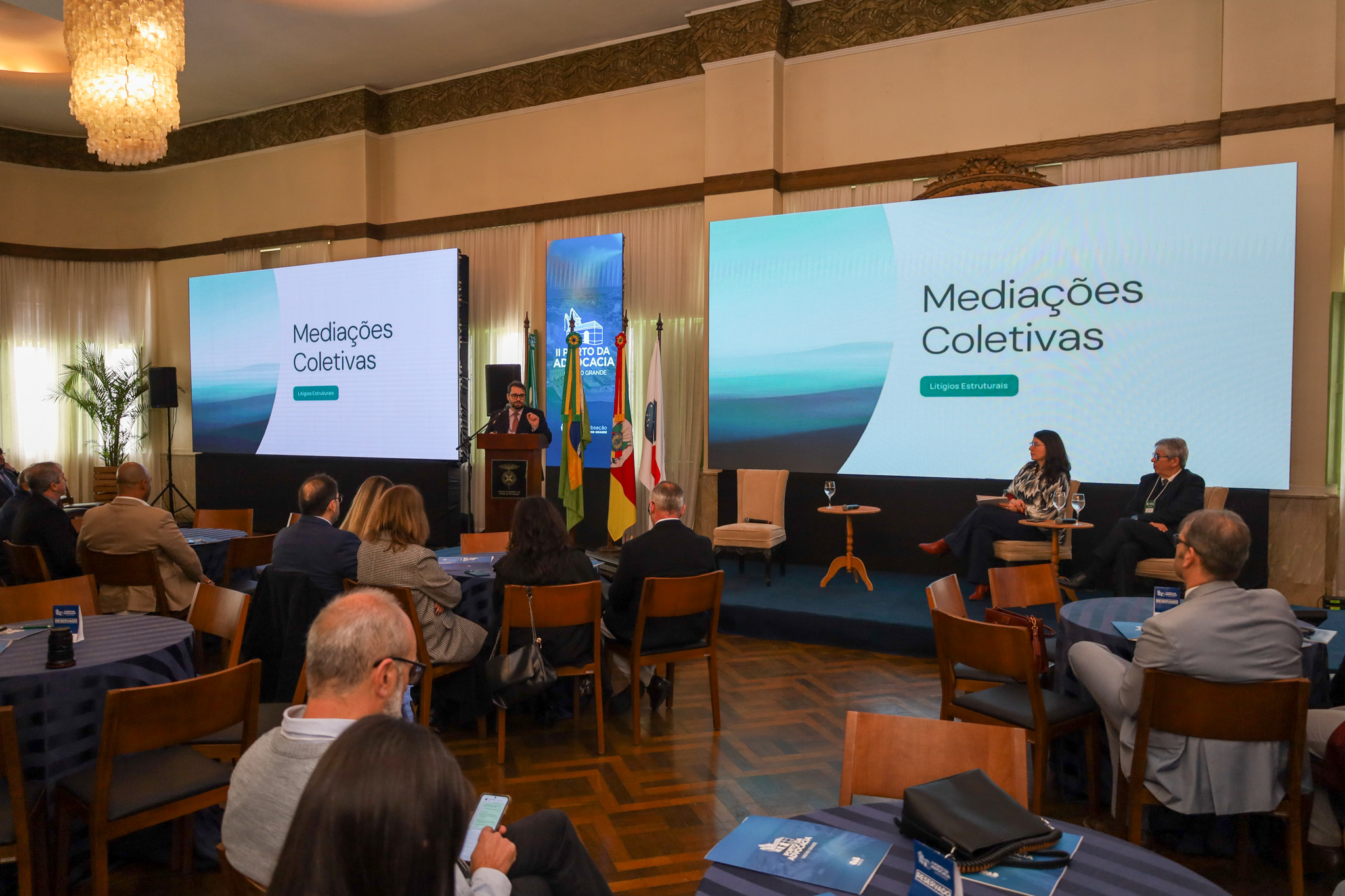 Foto em ângulo aberto, mostrando parte do público e o des. Alexandre falando, ao fundo.