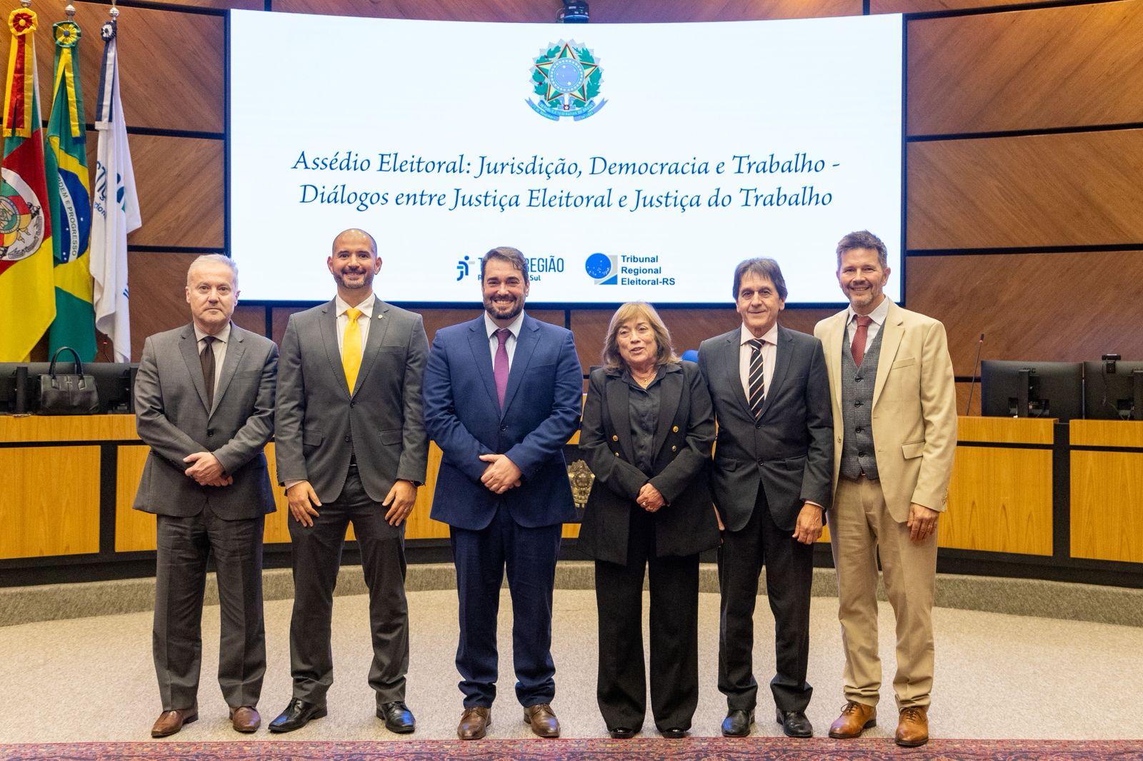 A foto mostra pessoas posando para foto lado a lado.