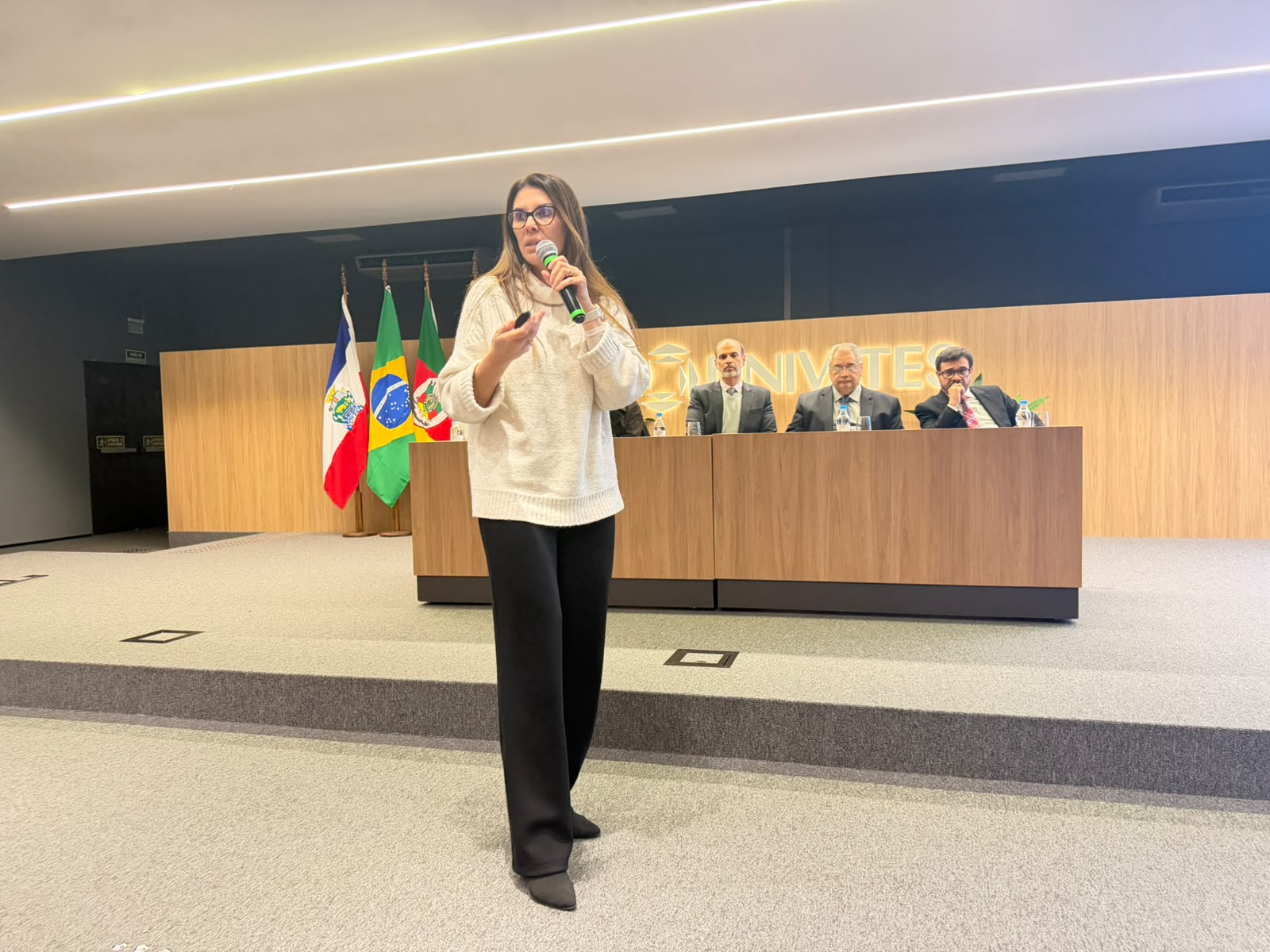 A foto mostra a juíza aline falando ao microfone
