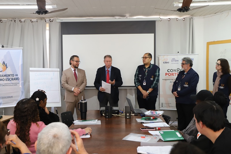 A fotografia mostra os magistrados e coordenadores do curso do Cibai, posicionados em frente ao quadro branco da sala de aula, conversando com os alunos.