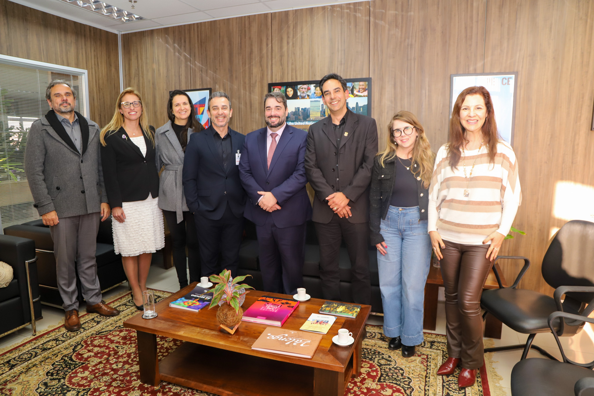 A foto mostra oito pessoas posando para foto, sendo quatro homens e quatro mulheres.