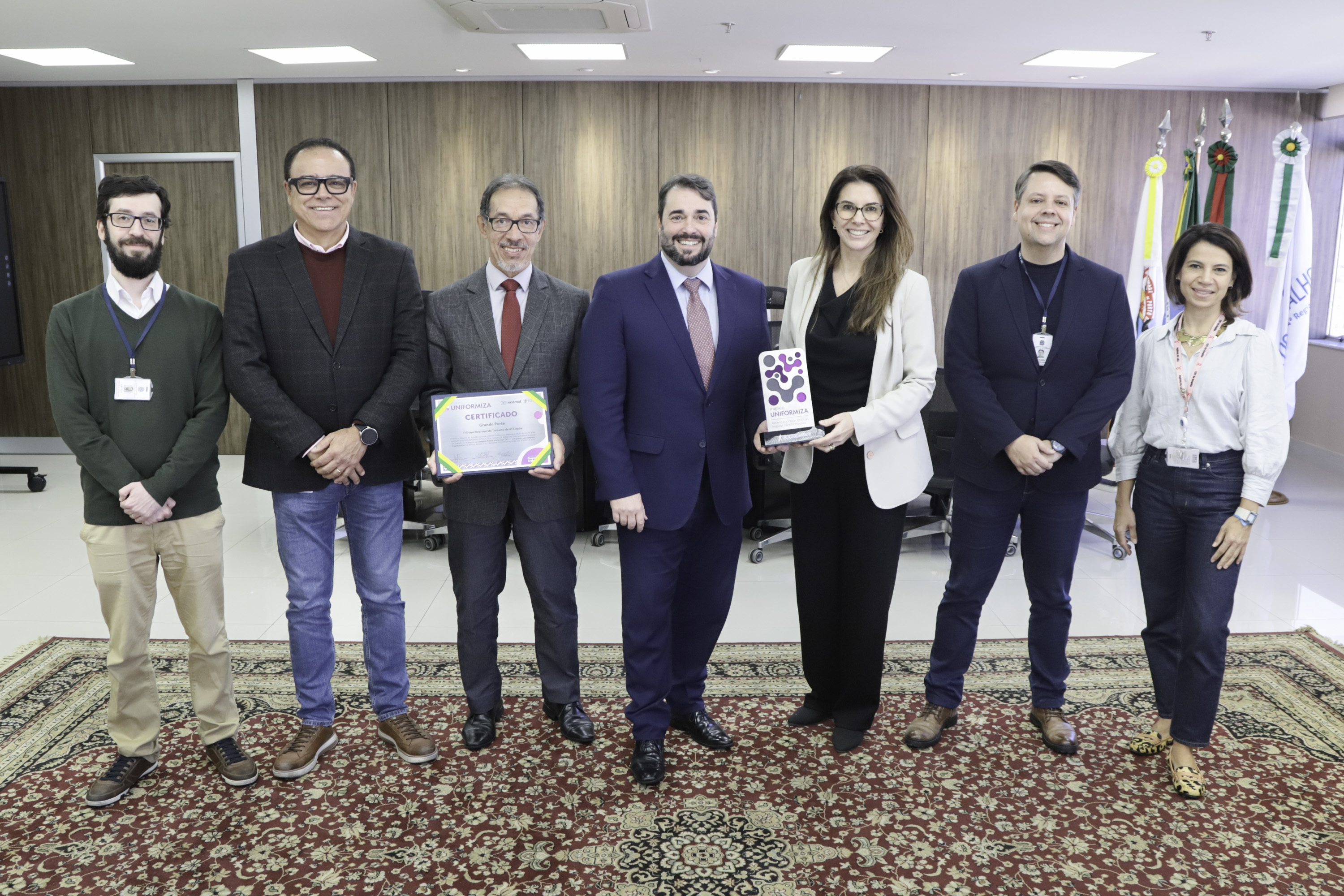 Participantes da reunião posam para a foto segurando o certificado e o trofeu da premiação.