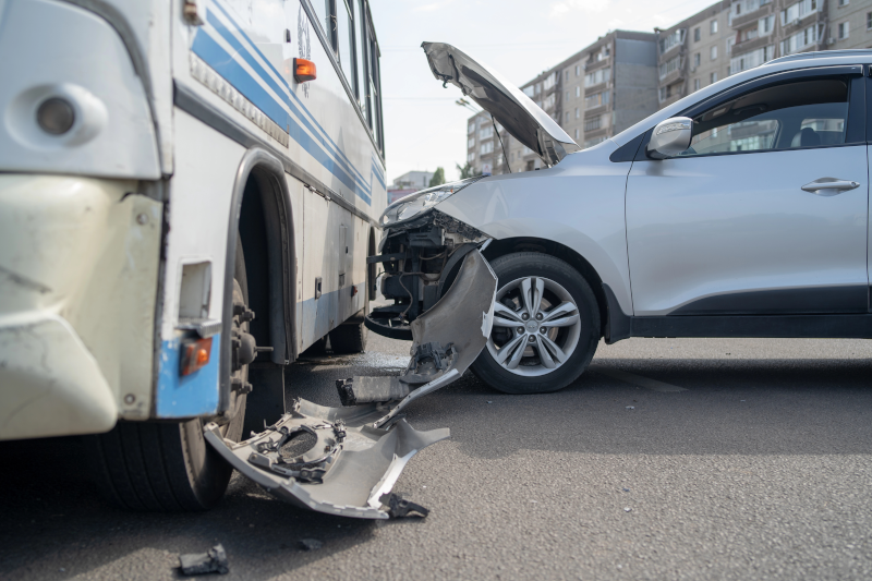 A fotografia um ônibus e um carro que colidiram.
