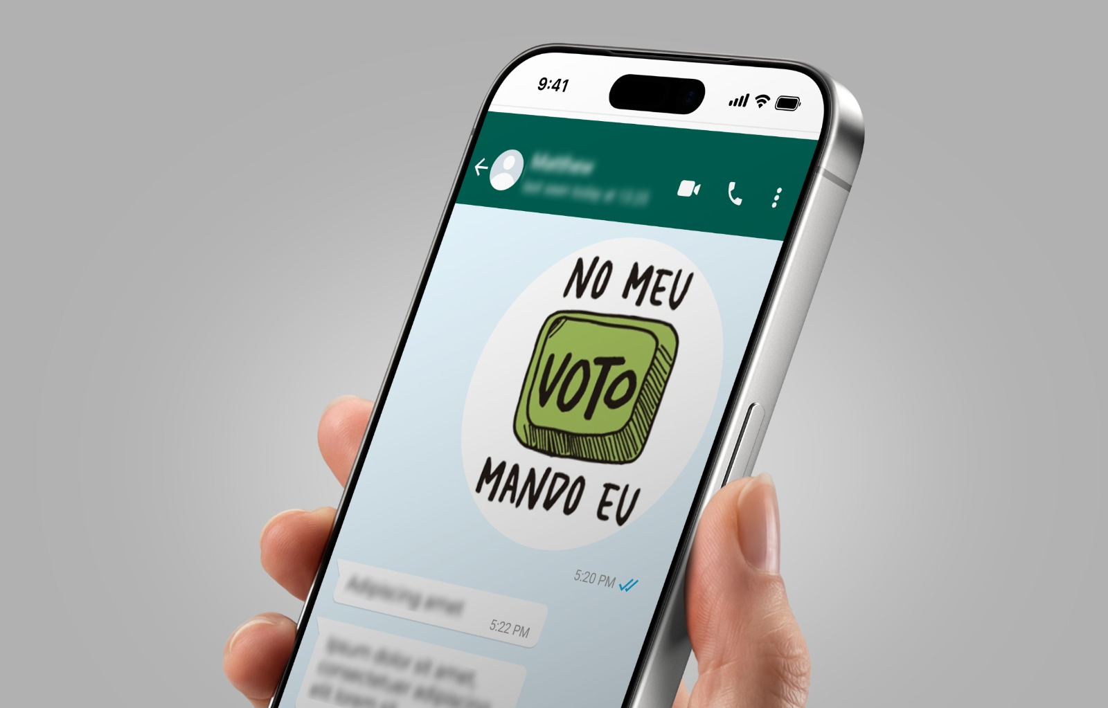 Mão segurando telefone celular com figurinha da campanha “No meu voto mando eu”.